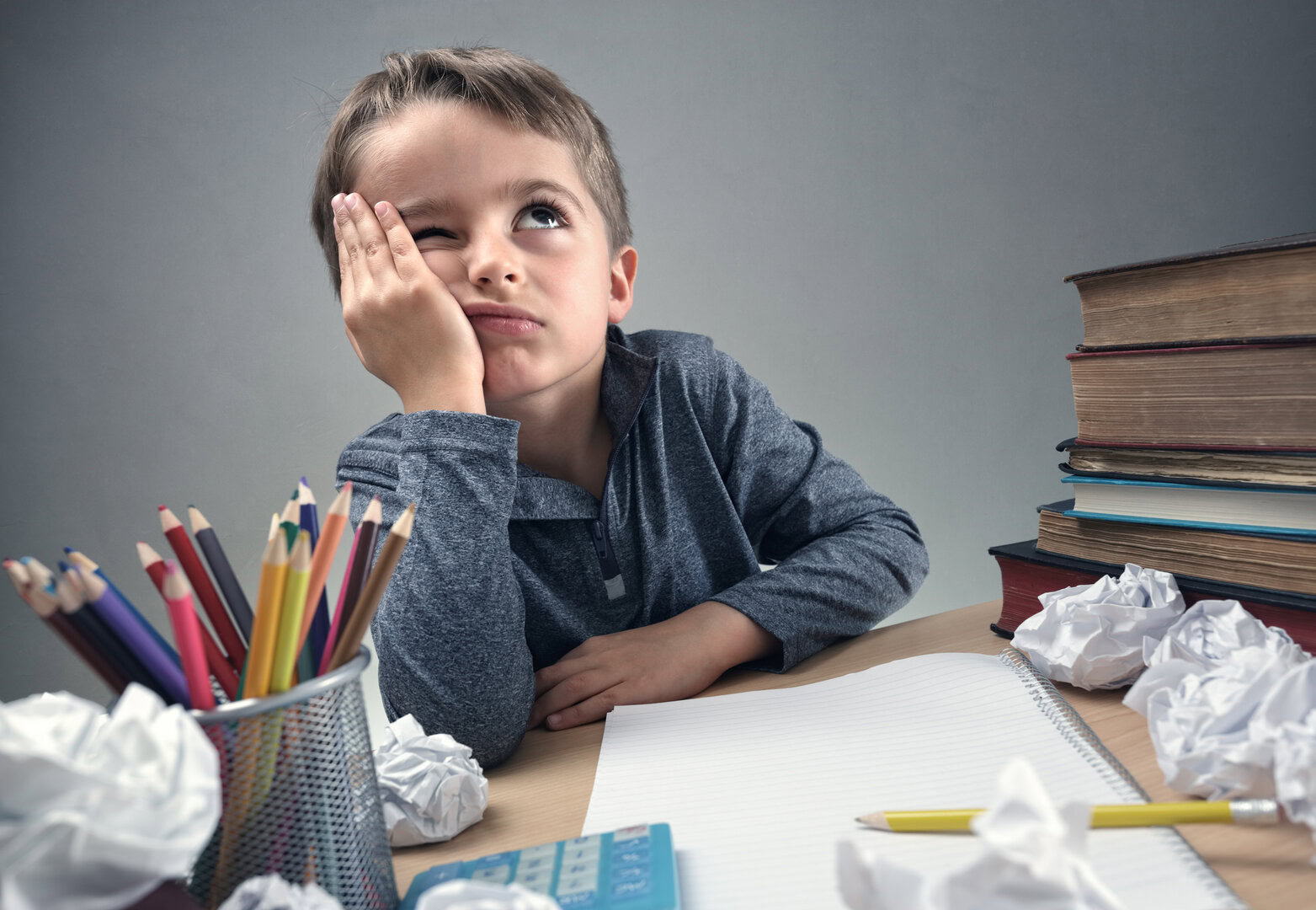 Enfant découragé devant ses devoirs à son bureau, illustrant les difficultés scolaires pouvant être accompagnées en ergothérapie.