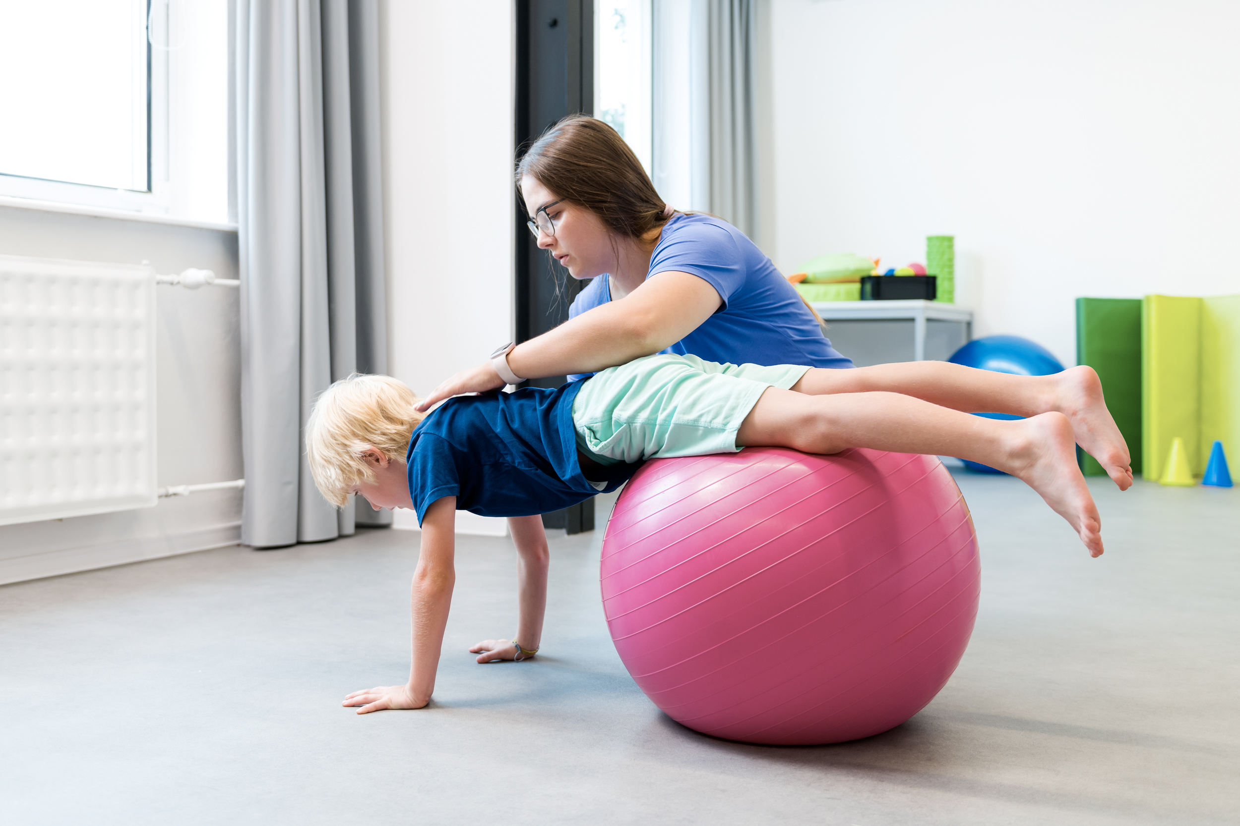 Ergothérapeute travaillant la motricité et l’équilibre avec un enfant sur un ballon en clinique à Drummondville